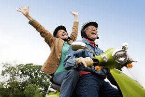 Senior couple having fun riding motor scooter. 