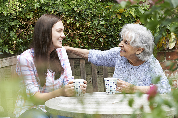 Granddaughter Relaxing With Grandmother In Garden