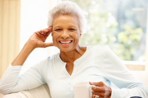 Senior woman at home drinking hot drink and smiling at the camera