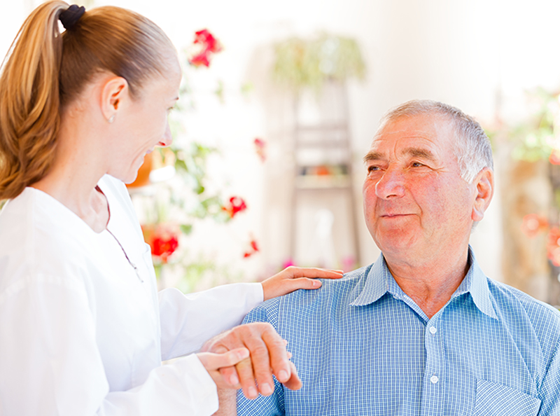 caregiver assisting senior man with Parkinson's