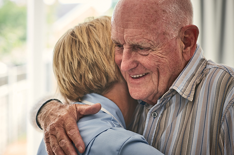 Female home carer hugging senior male with dementia