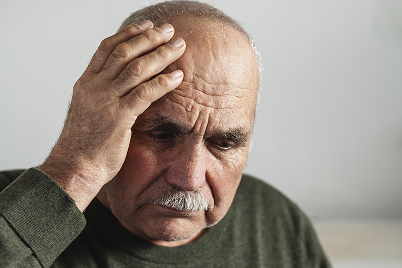 An older man holds his head to indicate memory problems