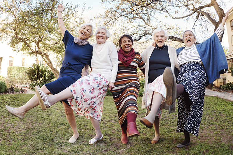 A group of happy elderly women dance together outside