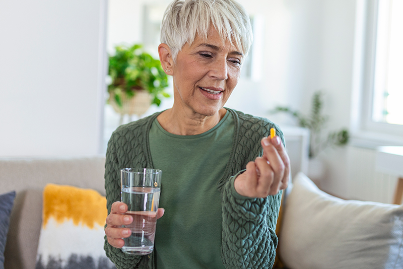 Lady holding vitamin and glass of water