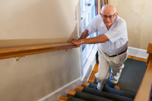 Senior man walking up stairs using a hand railing