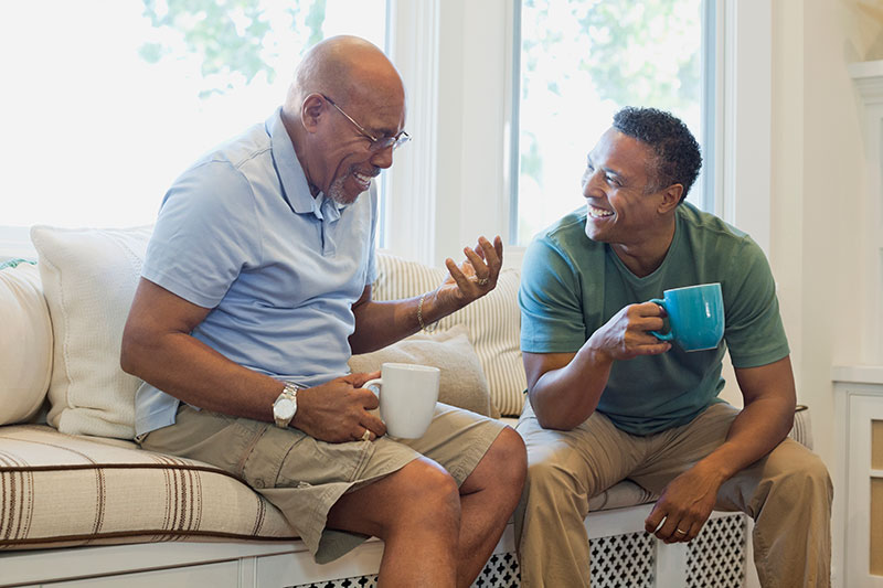 A young man smiles as he implements techniques to effectively respond to his father, who is experiencing dementia and conversation looping.