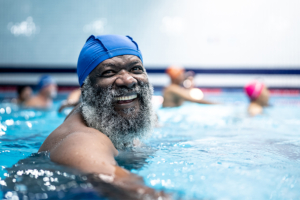 A senior smiles as he swims for his daily senior exercise.