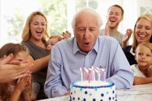 Birthday celebrations for seniors help people enjoy their special day to the fullest, as this gentleman is doing as he blows out the candles on his cake with his family cheering him on.
