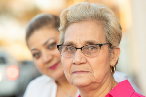 An adult daughter experiencing firsthand the needs of family caregivers stands behind her mother.