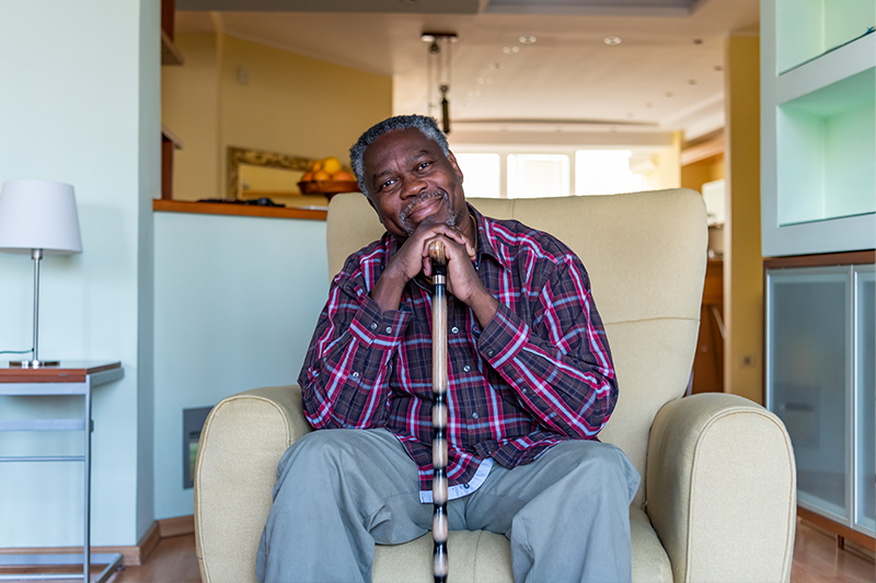 A man who struggles with the effects of a sedentary lifestyle in seniors sits in a chair at home.