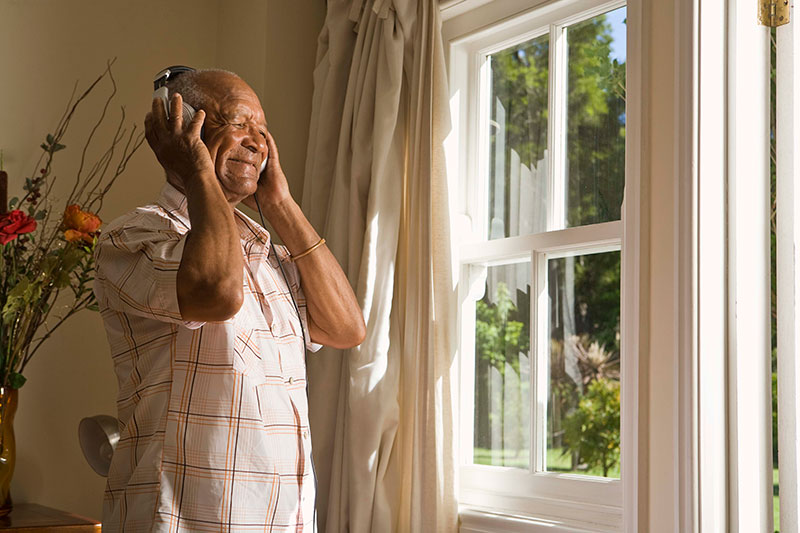 An older adult hums to himself while listening to a favorite song as he is about to use mental singing as non-medication Parkinson’s therapy.