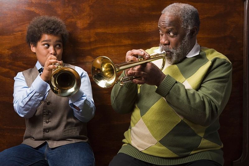 A senior practices a musical instrument with his grandson while exploring the connection between music and brain health.