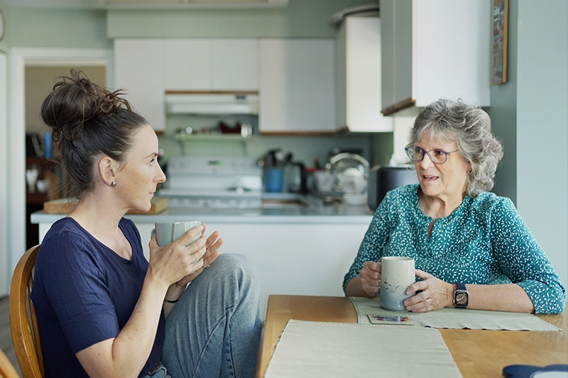 A woman recognizes early dementia warning signs while having coffee with her aging mother.